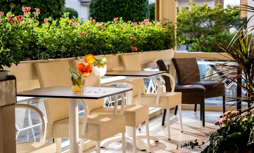 - deux tables et des chaises sur une terrasse fleurie dans l'établissement Hotel Laurin, à Lido di Jesolo