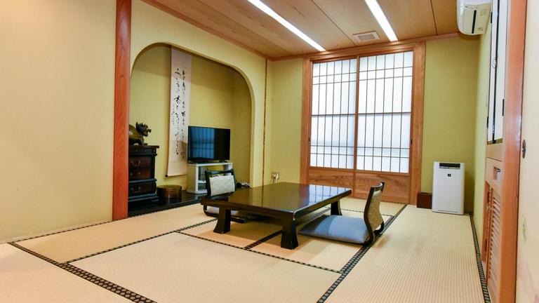 un salon avec une table et une télévision dans l'établissement Hamazen Ryokan, à Hinagu