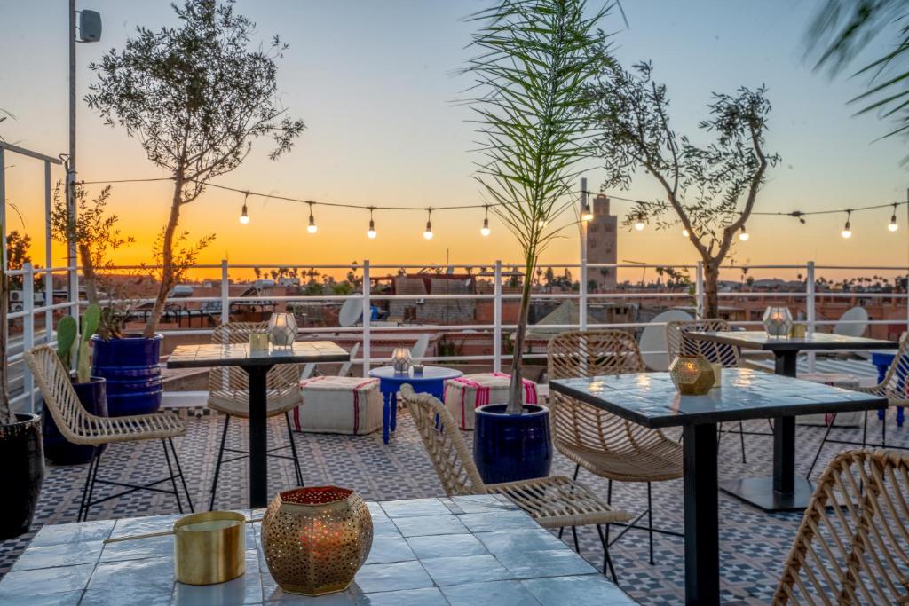 d'une terrasse avec des tables et des chaises et le coucher de soleil en arrière-plan. dans l'établissement BÔ Riad Boutique Hotel & Spa, à Marrakech