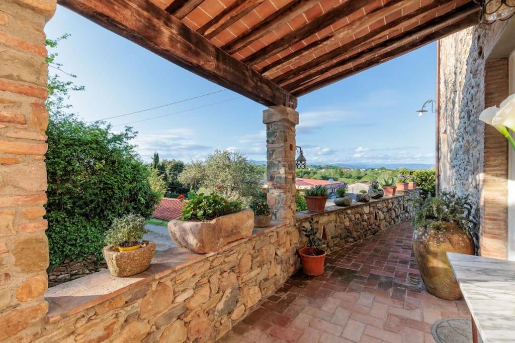 un patio extérieur avec un mur en pierre et des plantes en pot dans l'établissement Villa Aperitivo, Romantic and Panoramic Stone Farm, à Capannori