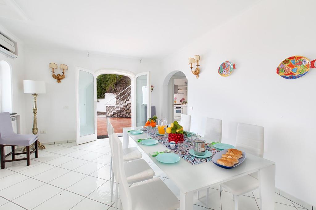 une salle à manger blanche avec une table et des chaises blanches dans l'établissement YourHome - Villa Triludonia, à Massa Lubrense