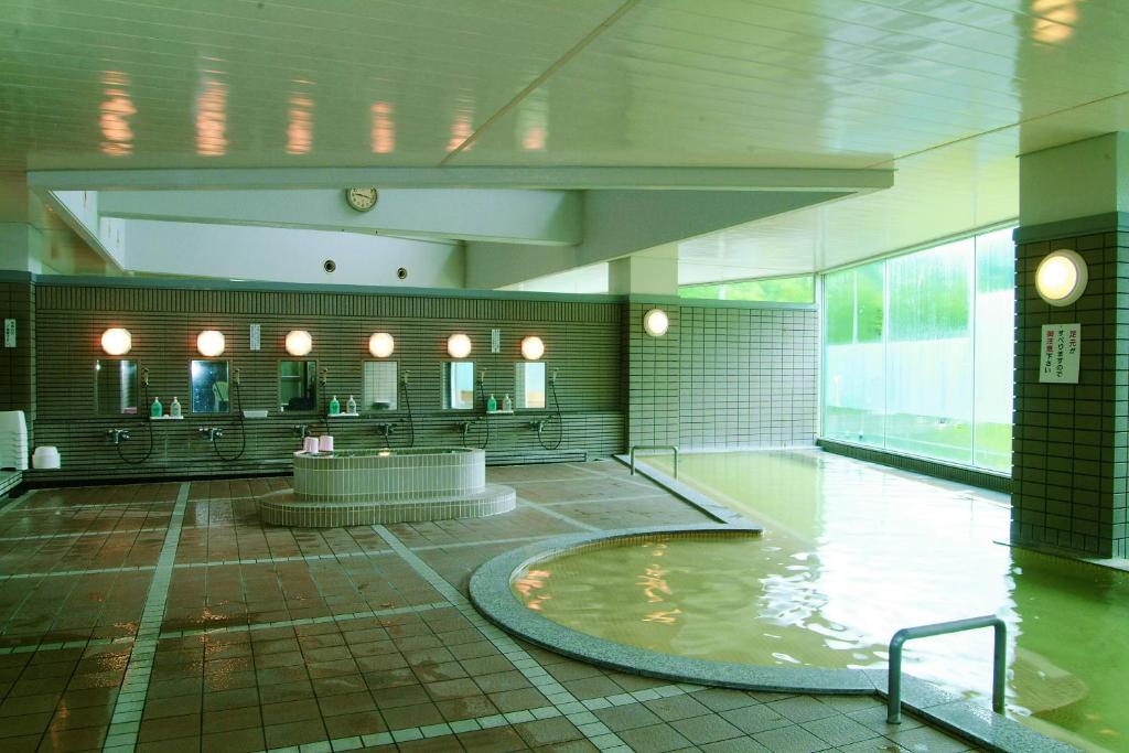 une grande chambre avec piscine d'eau dans un bâtiment dans l'établissement Horoshin Onsen Hotarukan, à Numata