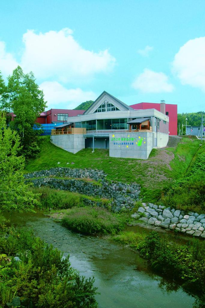 un bâtiment avec une rivière devant lui dans l'établissement Horoshin Onsen Hotarukan, à Numata