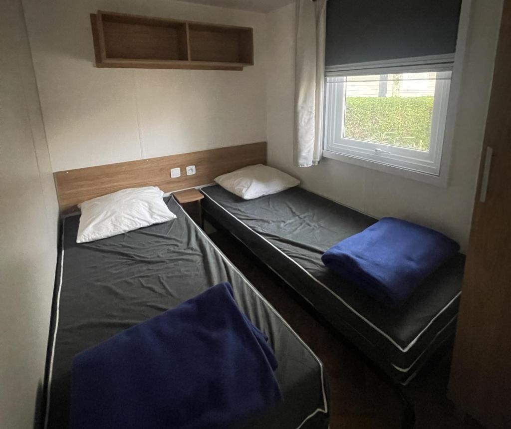 deux lits dans une petite pièce avec une fenêtre dans l'établissement Mobil-Home Bougainvilliers 1, à Valras-Plage 2 autres photos