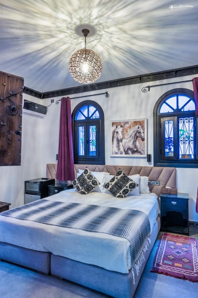 une chambre avec un grand lit et un lustre dans l'établissement Riad El Palacio & Spa Chaouen, à Chefchaouen