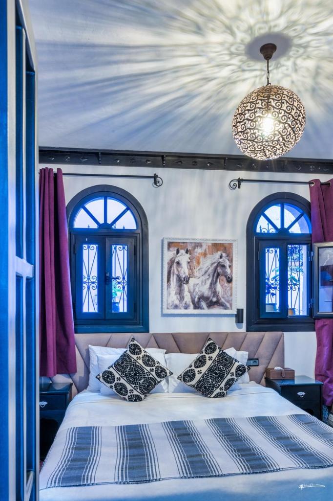 - une chambre avec un lit, deux fenêtres et un lustre dans l'établissement Riad El Palacio & Spa Chaouen, à Chefchaouen 37 autres photos