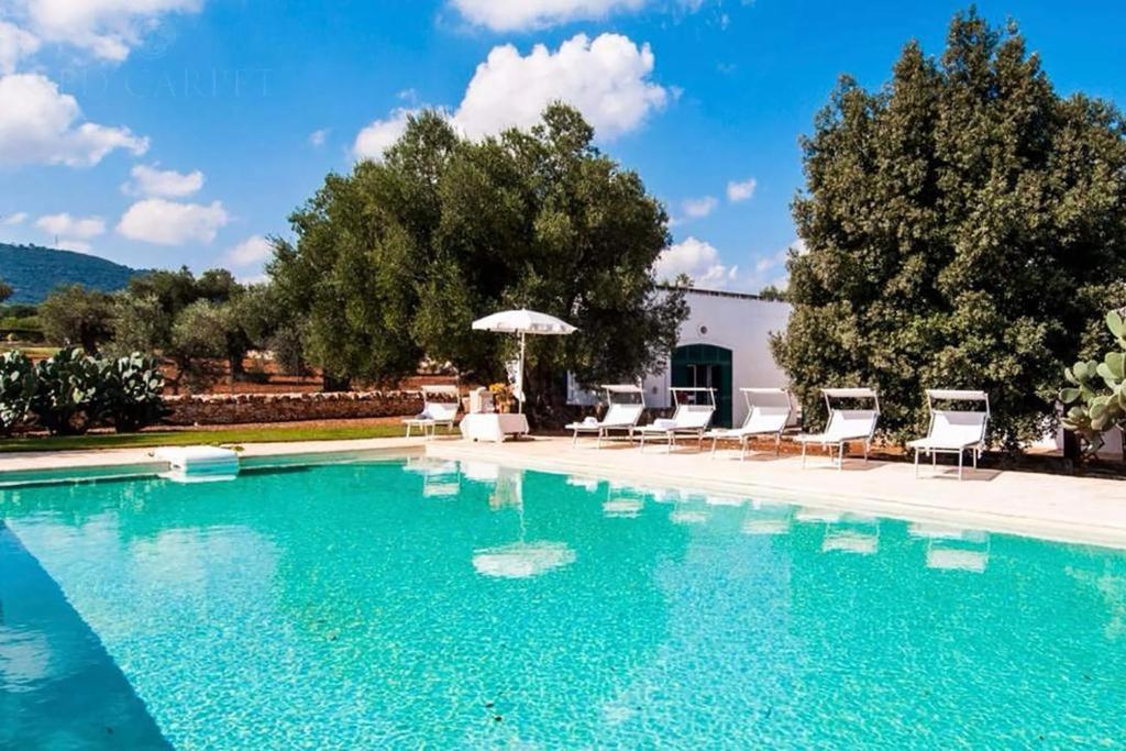 une grande piscine avec des chaises et un parasol dans l'établissement Masseria Terramare, à Macchia di Monte