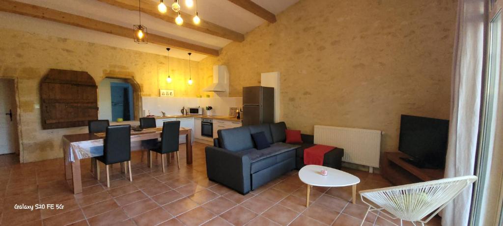 une cuisine et un salon avec un canapé et une table dans l'établissement La Vigneraie de Laura: Gîte Entre Vignes et Chênes, à Sainte-Colombe