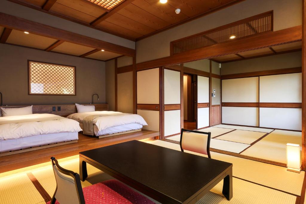 une chambre avec deux lits et une table et des chaises dans l'établissement Beautiful Japanese Garden Kagetsu, à Fuefuki