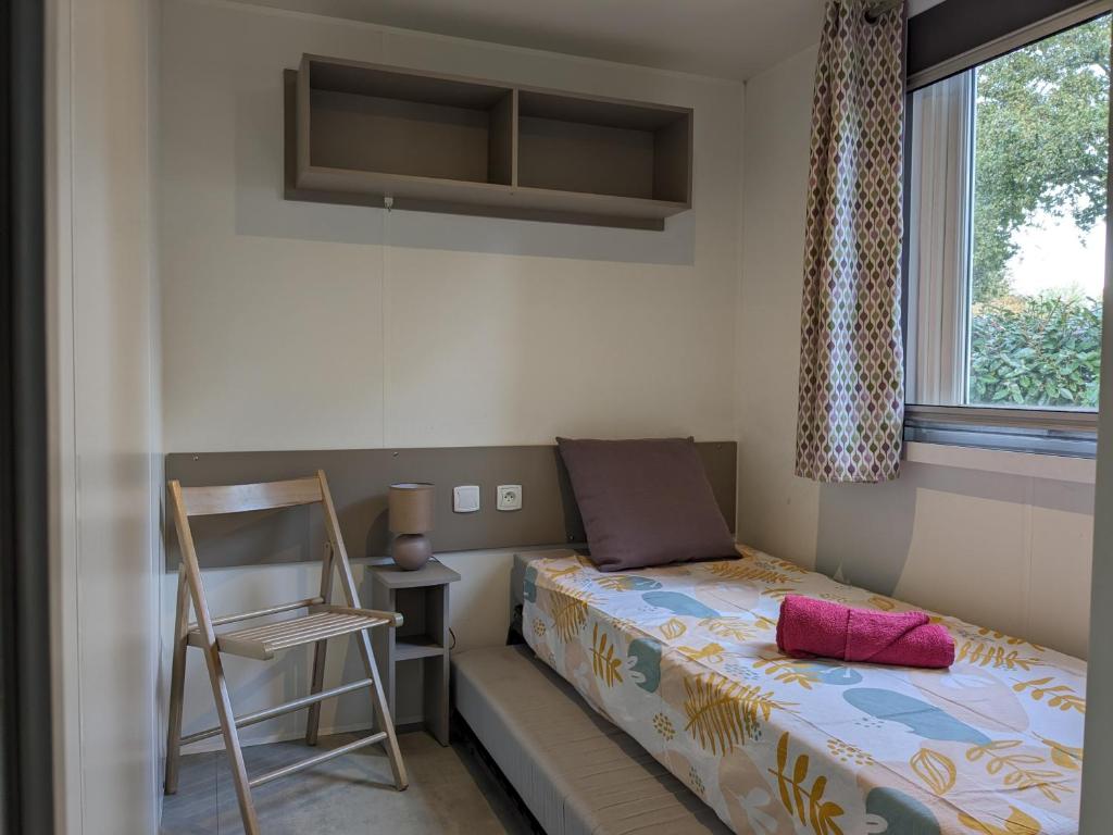 une petite chambre avec un lit et une chaise dans l'établissement mobil home 562 3 ch proche forêt village 4 étoiles Siblu La Reserve, à Gastes