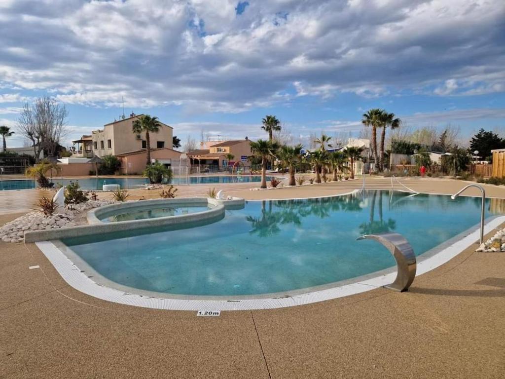 - une grande piscine dans un complexe avec des palmiers dans l'établissement Super mobil-home aux Sables du Midi, à Sérignan