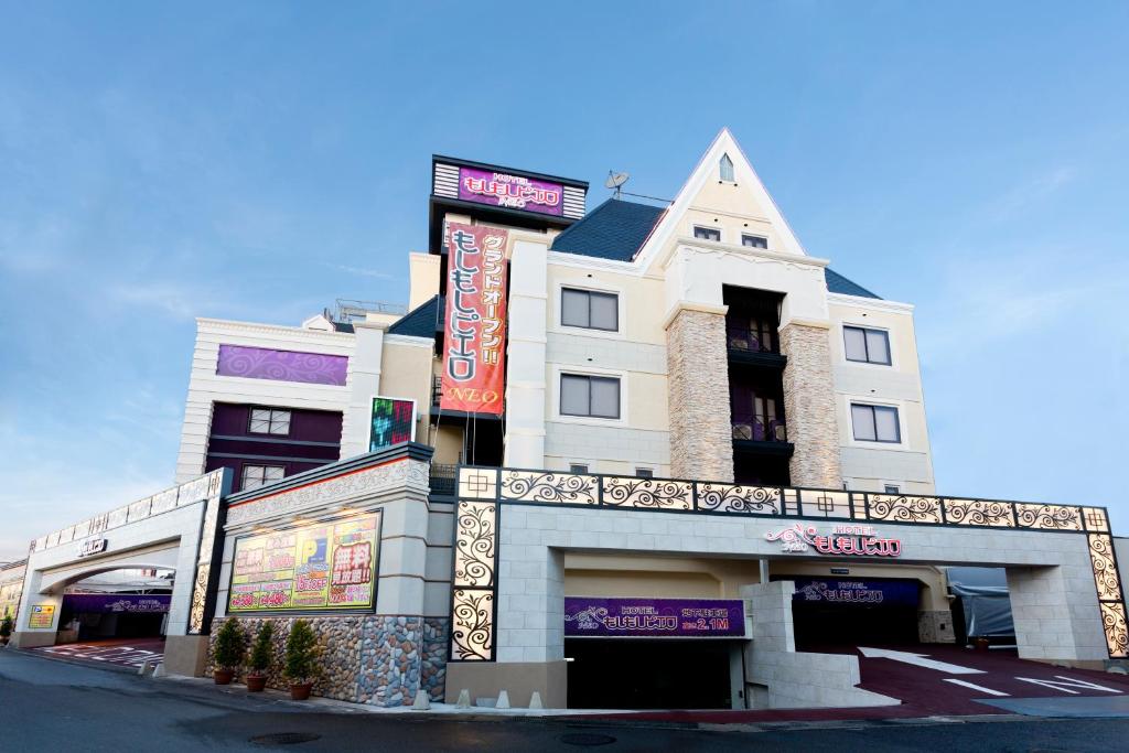 un bâtiment blanc avec une pancarte sur le côté dans l'établissement もしもしピエロ NEO 京都店, à Kyoto