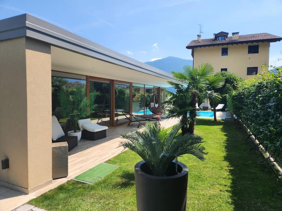 une maison avec une terrasse agrémentée de palmiers dans la cour dans l'établissement villa relax, à Riva del Garda