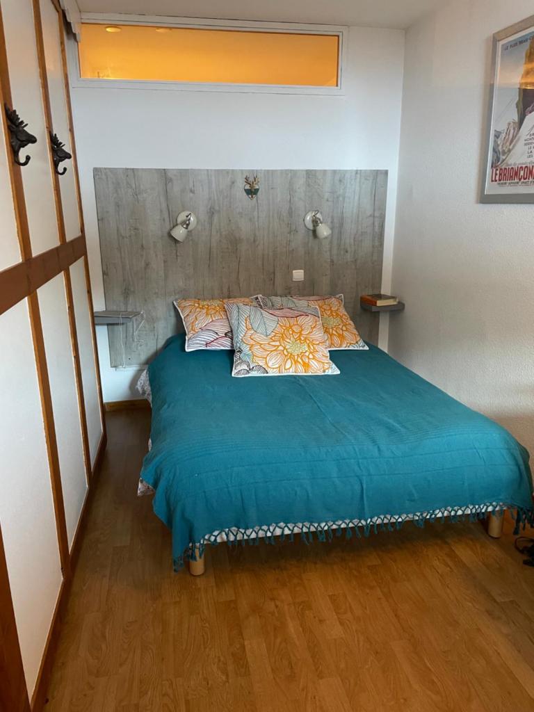 une chambre avec un lit avec des draps et des oreillers bleus dans l'établissement Puy St Vincent 1800 au pied des pistes, à Puy-Saint-Vincent