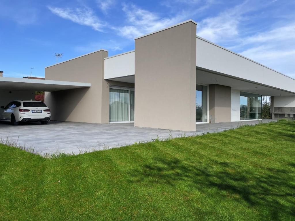 une maison blanche avec une voiture garée dans l'allée dans l'établissement STIMAHome villa con piscina privata, à Veggiano