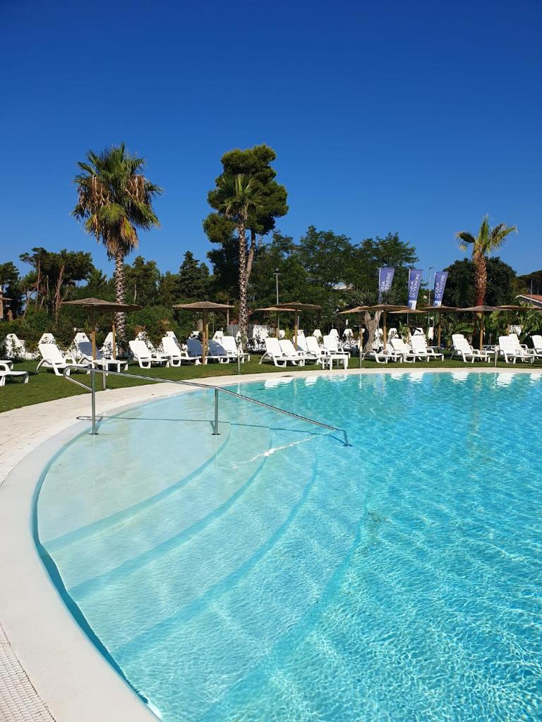une grande piscine avec chaises et palmiers dans l'établissement Resort Acqua di Venere, à Paestum