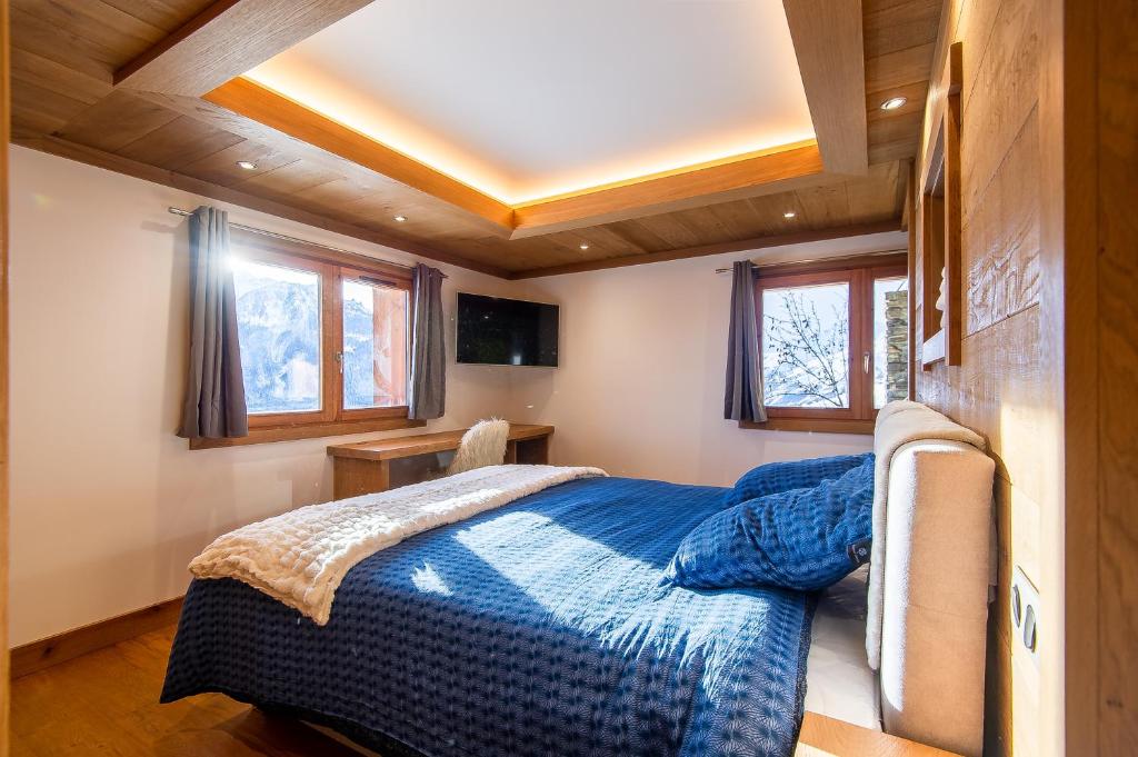 une chambre avec un lit avec une couverture bleue dans l'établissement Chalet Evidence, à Montvalezan 34 autres photos