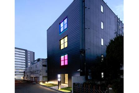 un bâtiment noir avec des fenêtres éclairées dans une rue dans l'établissement Hotel UNO Nishikawaguchi Nishiguchi, à Kawaguchi