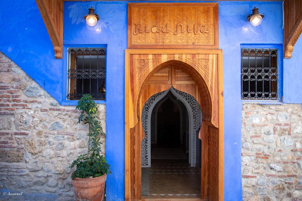 une entrée dans un bâtiment bleu avec une porte en bois dans l'établissement Riad Nila, à Chefchaouen