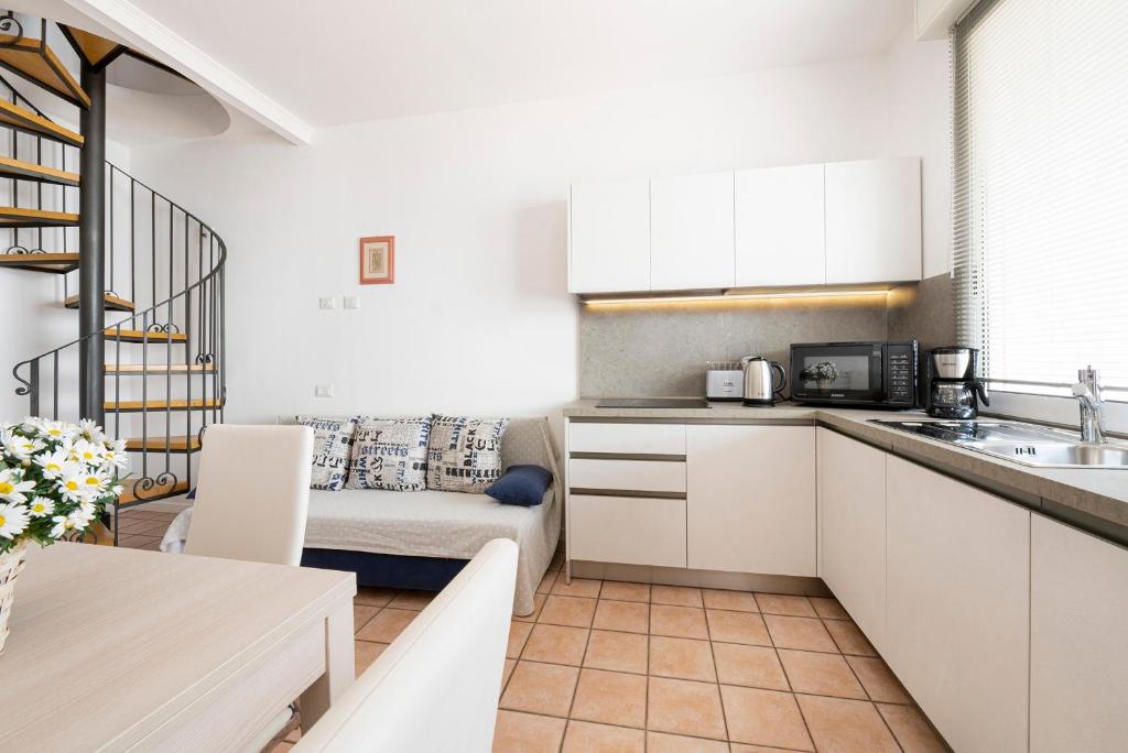 une cuisine avec des armoires blanches et un canapé dans une pièce dans l'établissement Residence Casa e Vela, à Oggebbio