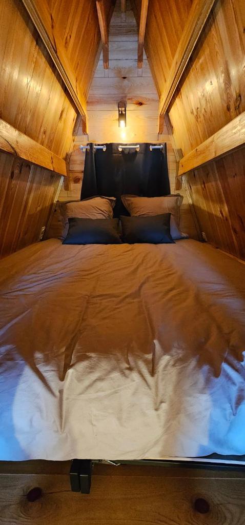 un grand lit dans une chambre avec un plafond en bois dans l'établissement Cabane Ardennaise, à Fromelennes