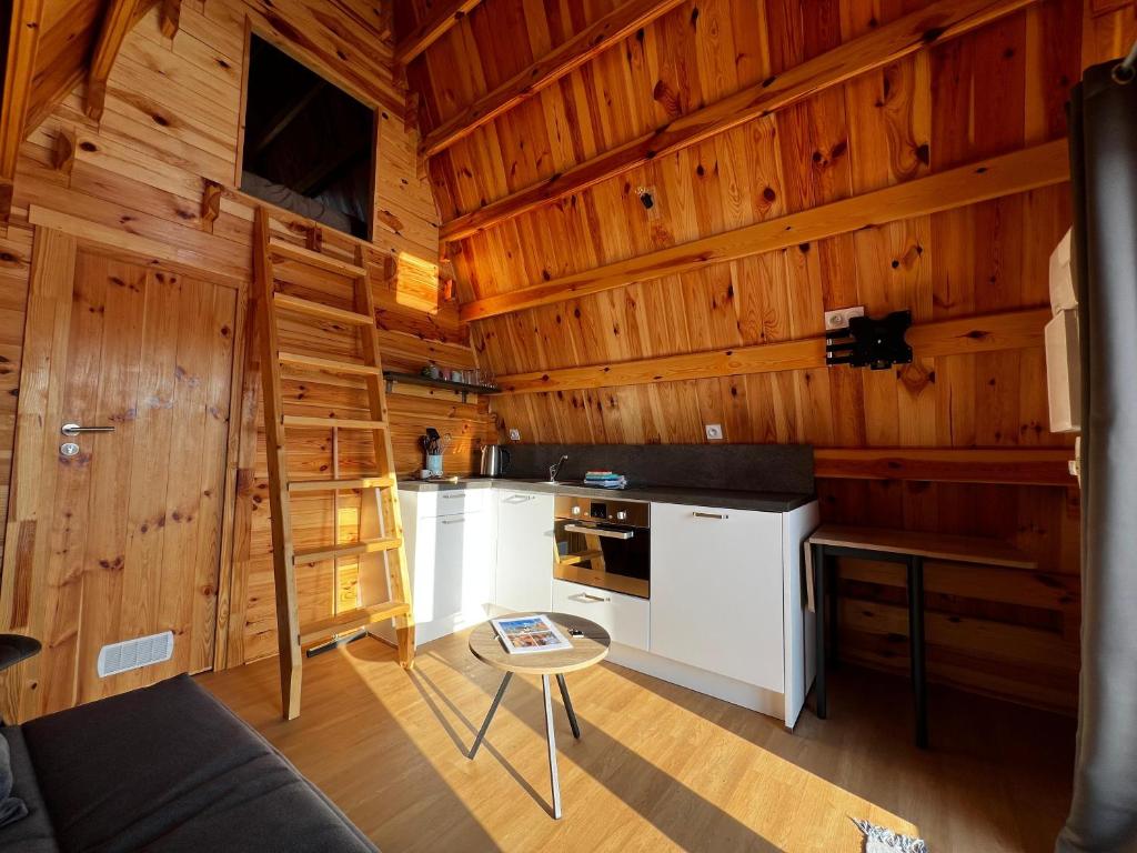 - une cuisine avec des murs en bois et un escalier dans une cabine dans l'établissement Cabane Ardennaise, à Fromelennes