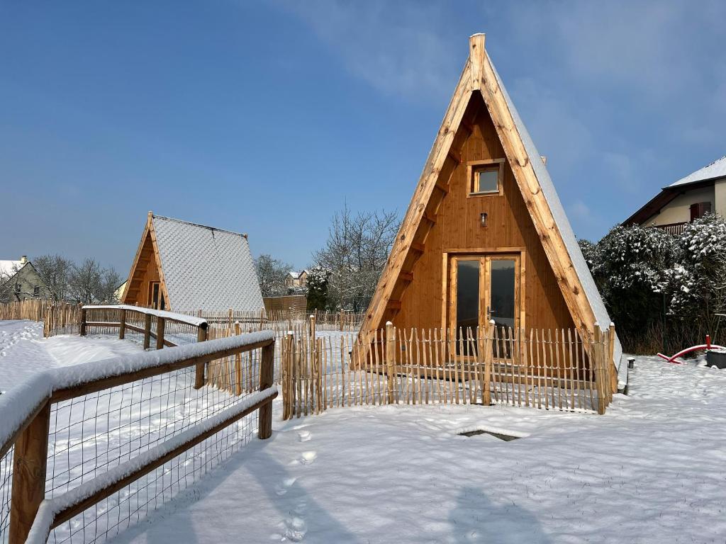 une maison en bois dans la neige avec une clôture dans l'établissement Cabane Ardennaise, à Fromelennes
