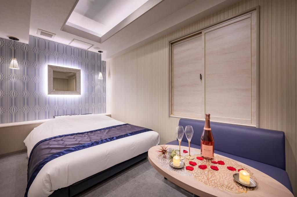 - une chambre avec un lit et une table avec une bouteille de vin dans l'établissement Hotel Plantan - Adult Only, à Tokyo