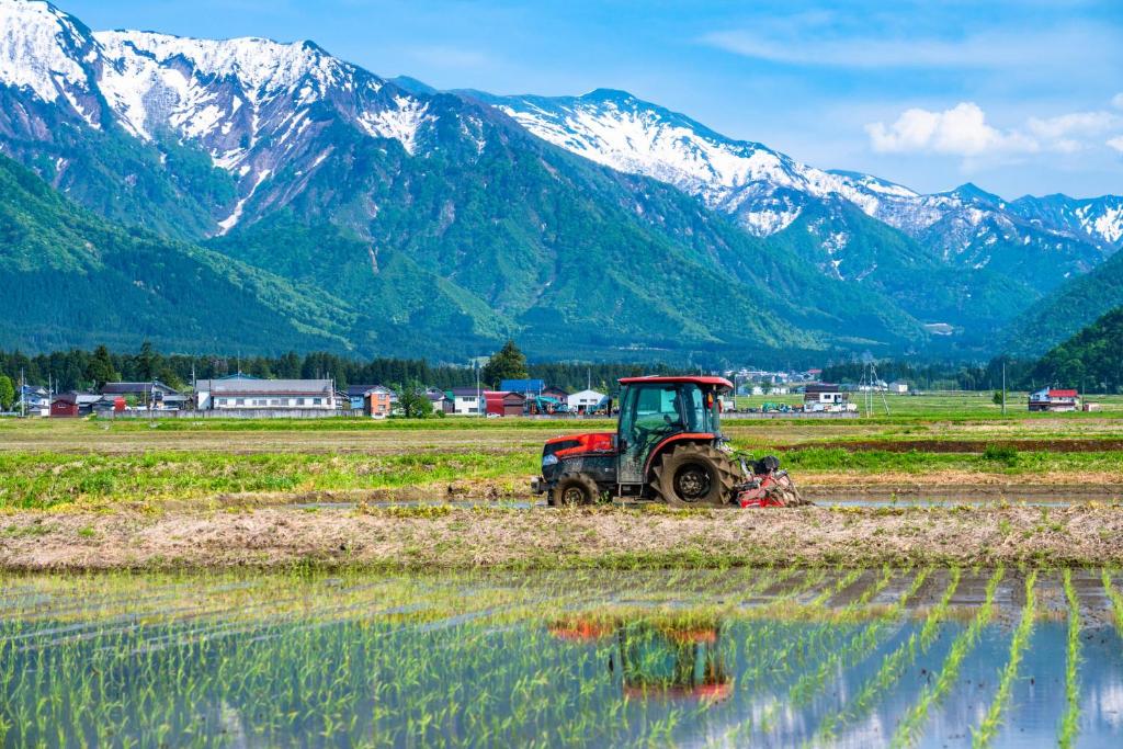 un tracteur dans un champ avec des montagnes en arrière-plan dans l'établissement Sakadojo, à Minami Uonuma