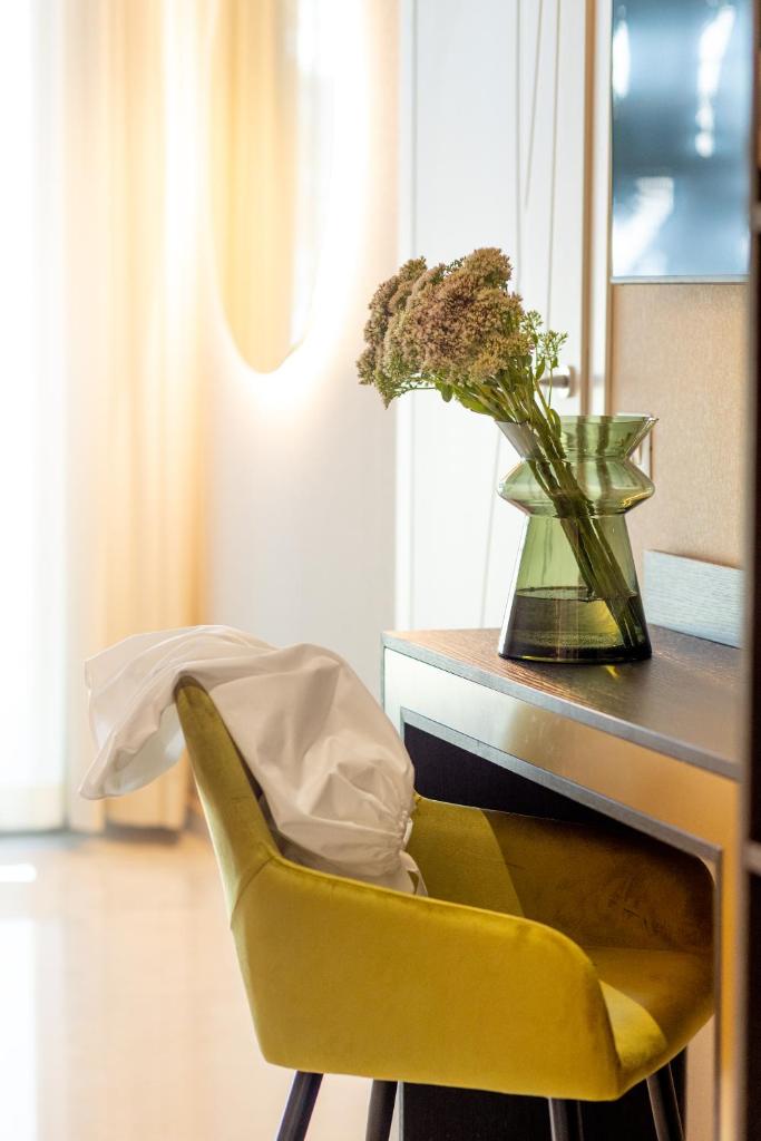 une chaise jaune à côté d'un bureau avec un vase de fleurs dans l'établissement Hotel Mondial, à Rimini 37 autres photos