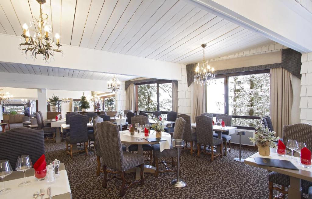 une salle à manger avec tables, chaises et fenêtres dans l'établissement Odalys Hotel New Solarium, à Courchevel
