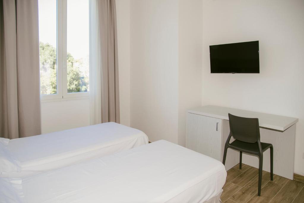 une chambre avec deux lits, un bureau et une chaise dans l'établissement Residence Altair - Serra degli Alimini, à Otrante