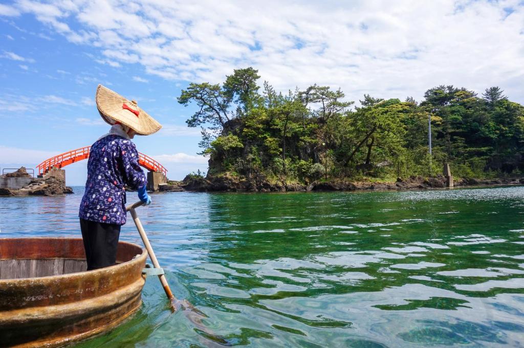 une femme dans un bateau dans l'eau dans l'établissement Sado Ryosou Minato, à Sado