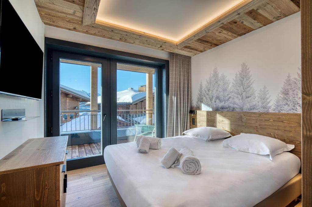une chambre avec un grand lit et une grande fenêtre dans l'établissement Lodge des Glaciers - La Rosière, à Montvalezan