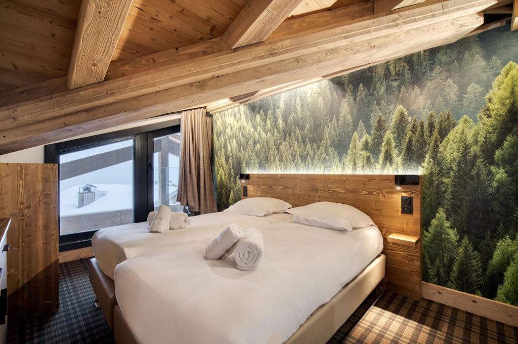 une chambre avec deux lits et un tableau au mur dans l'établissement Lodge des Glaciers - La Rosière, à Montvalezan