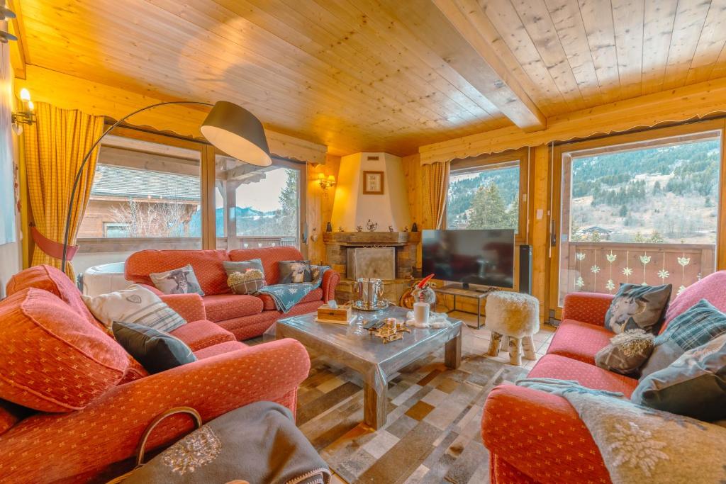 Il comprend un salon doté d'un mobilier rouge et d'une télévision. dans l'établissement chalet Amitie familial de luxe avec JACUZZI, HEBERGEMENT MULTIPASS ETE, WIFI fibre, 150 m des pistes de ski et randonnées, aux Gets