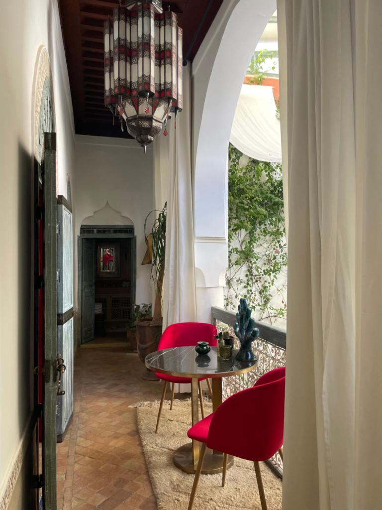 une salle à manger avec une table, des chaises et un lustre dans l'établissement Riad Dar Al Assad, à Marrakech