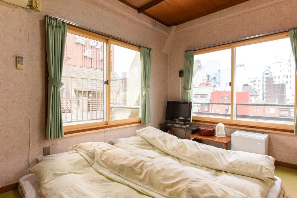 une chambre avec un lit et deux grandes fenêtres dans l'établissement Ryokan Mikawaya, à Tokyo