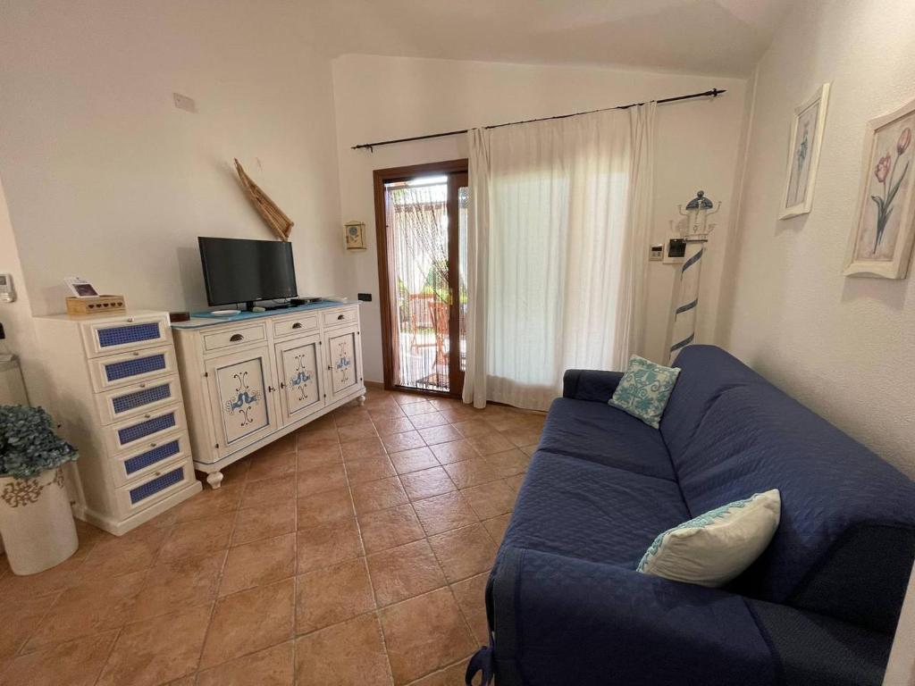 un salon avec un canapé bleu et une télévision dans l'établissement villa elena piscina privata, à Tanaunella