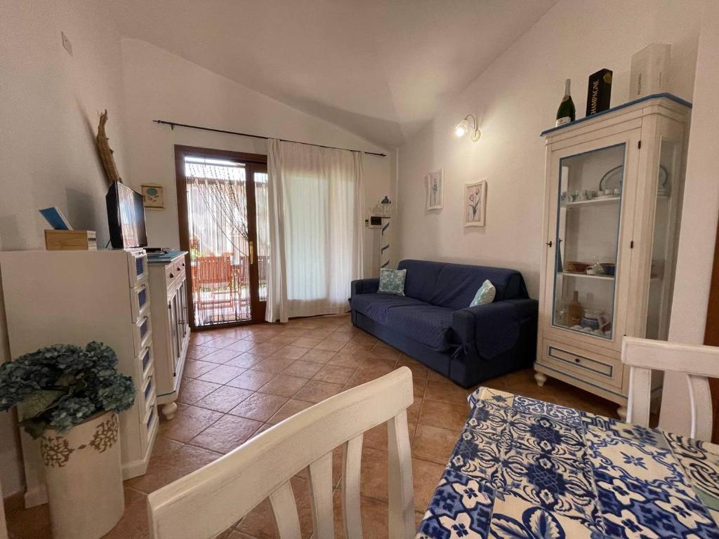 un salon avec un canapé bleu et une table dans l'établissement villa elena piscina privata, à Tanaunella