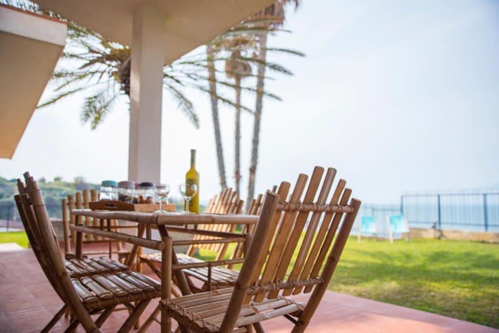 - une table et des chaises sur une terrasse couverte donnant sur l'océan dans l'établissement SERENDIPITY VILLA sea view, sun and Etna, à Agnone Bagni