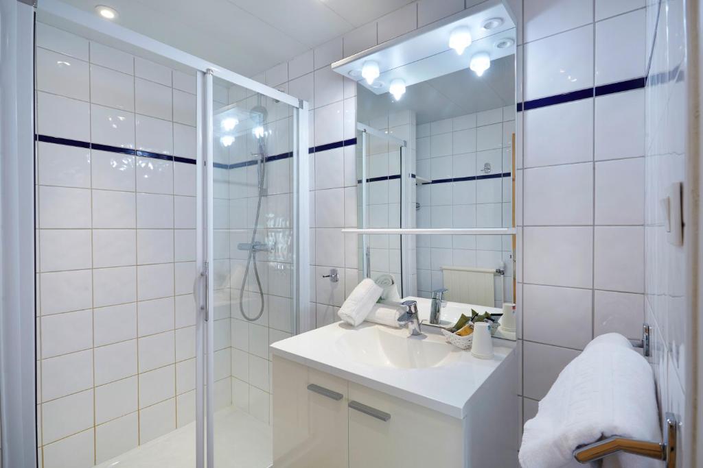 une salle de bain blanche avec un lavabo et une douche dans l'établissement Hôtel Eliova Le Chaix, à L'Alpe-d'Huez 27 autres photos