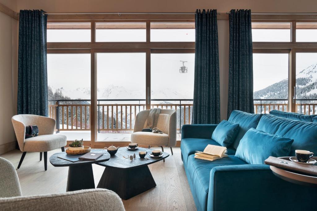 un salon avec un canapé bleu et une grande fenêtre dans l'établissement MGM Hôtels & Résidences - Résidence Manaka, à Aime La Plagne