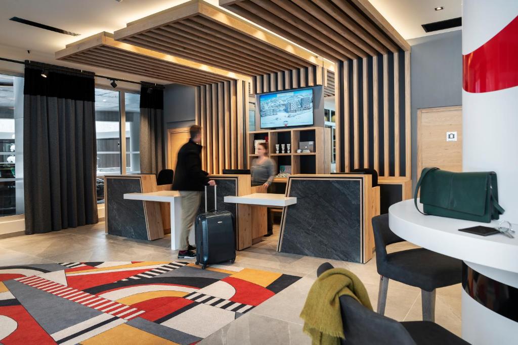 un hall avec deux personnes debout à un comptoir dans l'établissement MGM Hôtels & Résidences - Hôtel Alhéna, à Flaine