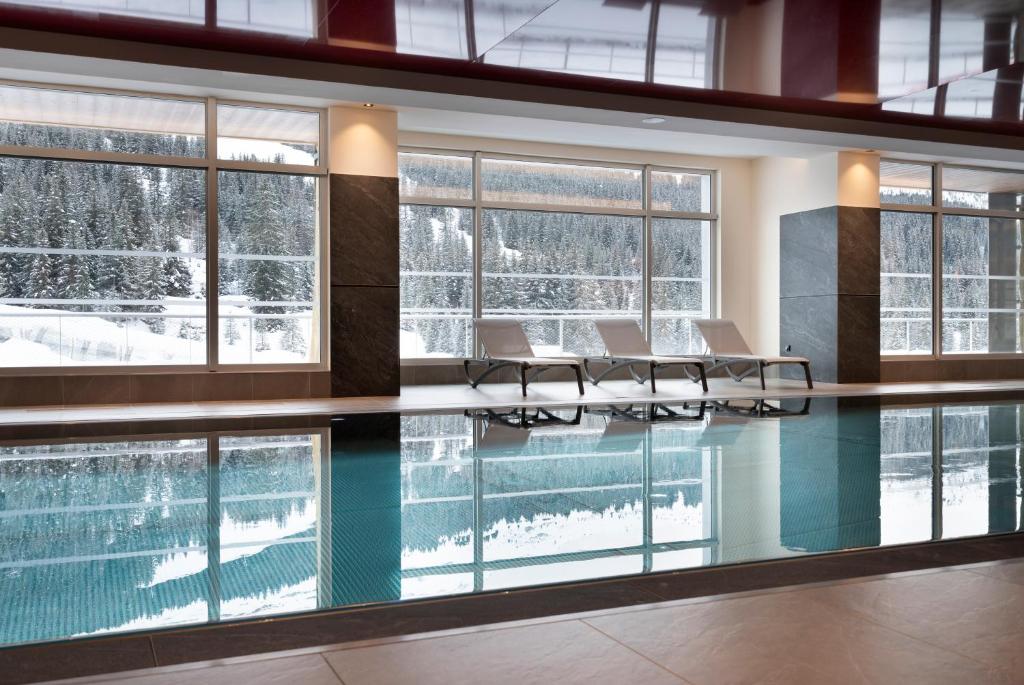une piscine avec tables et chaises dans un bâtiment dans l'établissement MGM Hôtels & Résidences - Résidence Alhéna, à Flaine