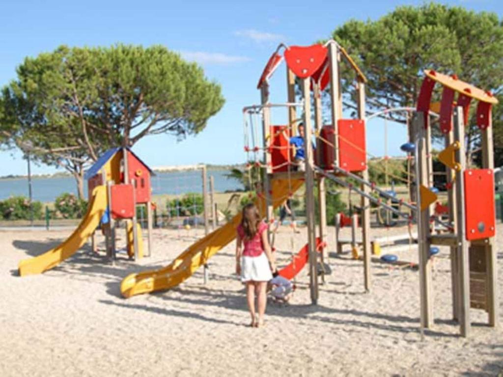 Une petite fille se promène devant une aire de jeux dans l'établissement Mobil-home 3 chambres 6-8 pers - Camping Lac des Rêves, Lattes, à Lattes