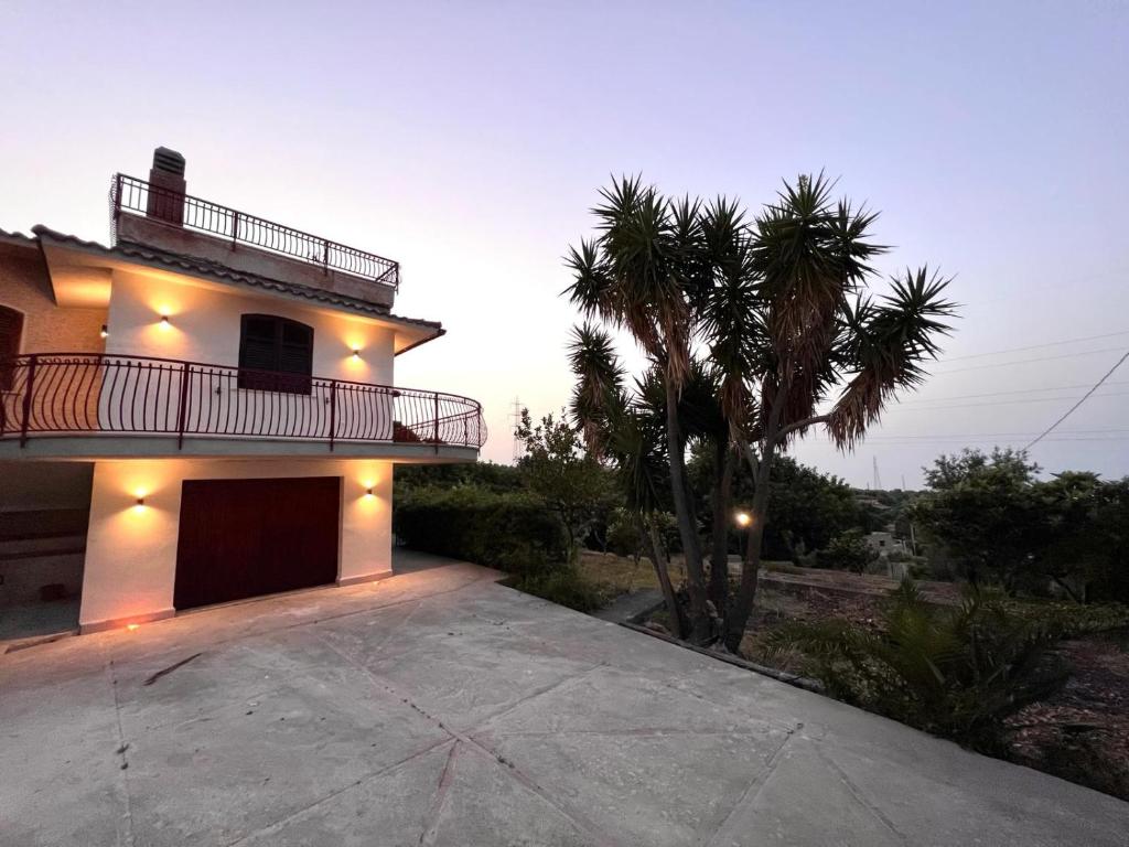 une grande maison avec un palmier en face dans l'établissement Villa La Terrazza Sul Mare di Trabia, à Trabia