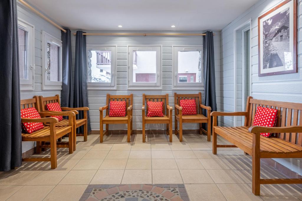 une rangée de chaises avec des coussins rouges dans une pièce dans l'établissement Résidence Pierre & Vacances Le Thabor, à Valmeinier