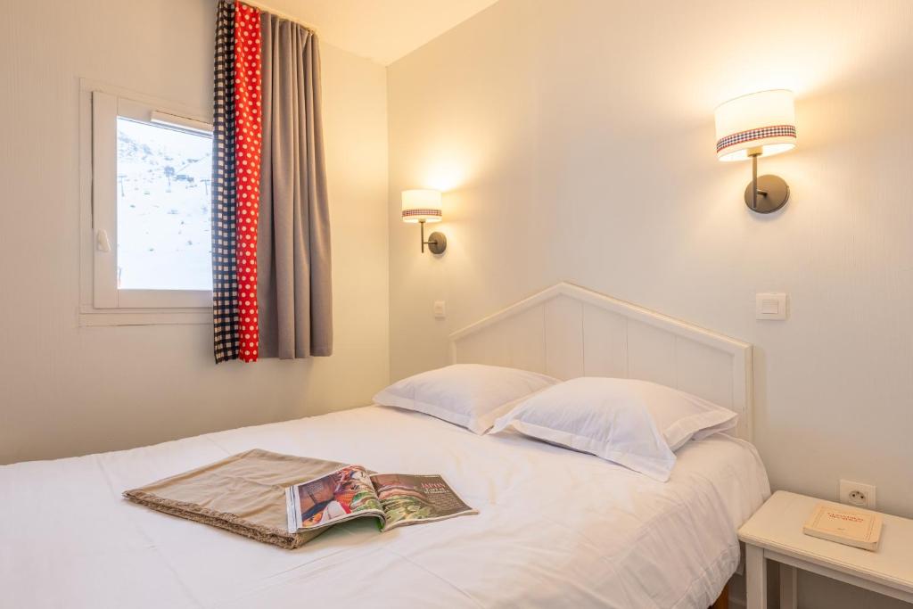 - une chambre avec un lit et un magazine dans l'établissement Résidence Pierre & Vacances Le Thabor, à Valmeinier