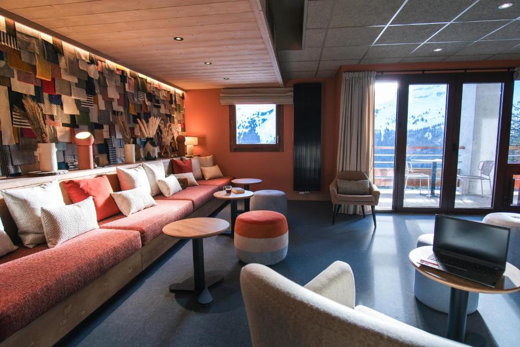 - une salle d'attente avec un canapé, des tables et des chaises dans l'établissement Belambra Clubs Flaine Panorama, à Flaine